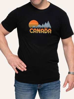 Man wearing black camping t-shirt with Canada, sunset, canoe, and mountains - Made in Canada by Choose Canadian Apparel Co