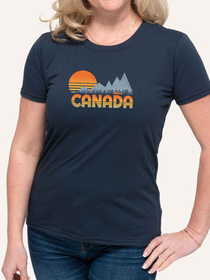 Woman wearing blue camping t-shirt with CANADA slogan and orange sunset, mountain, trees and canoe graphic - Made in Canada by Choose Canadian Apparel Co