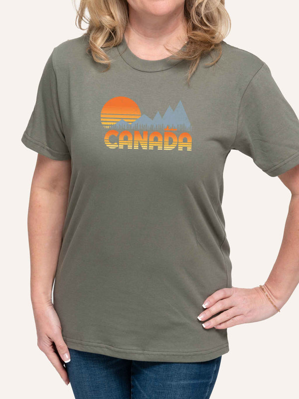Woman wearing green camping t-shirt with Canada, sunset, canoe, and mountains - Made in Canada by Choose Canadian Apparel Co